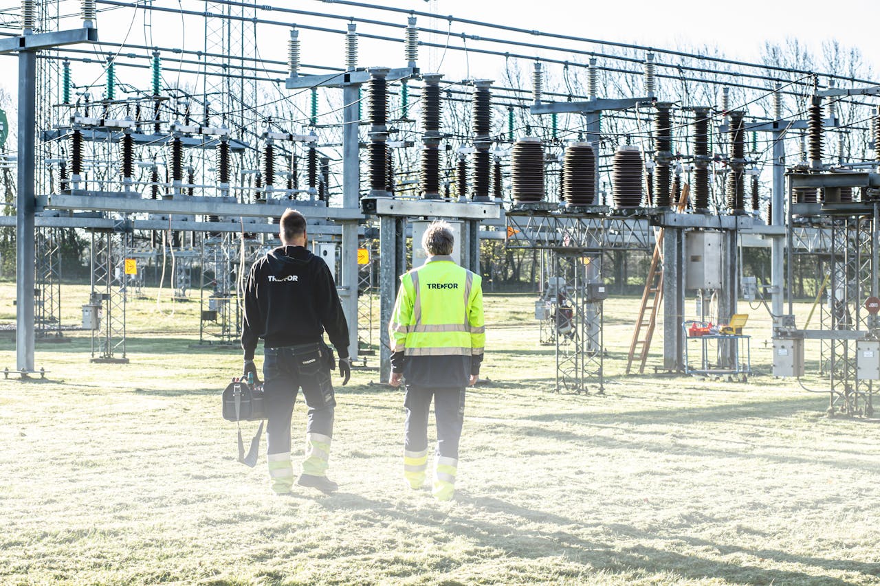 client-satisfaction-img Two workers inspect an outdoor electrical substation, emphasizing safety and maintenance.