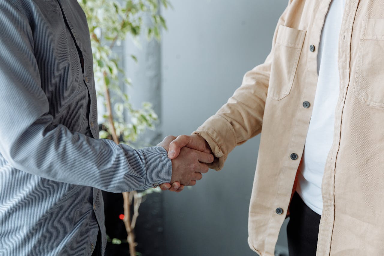 services-01 A close-up image of two businesspeople shaking hands in an office environment symbolizing agreement and partnership.